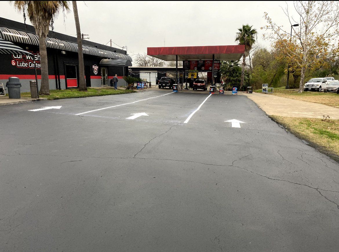 Empty parking lot leading to a gas station canopy and pumps on an overcast day
