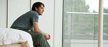 Young man sitting on edge of bed — Counseling Services in Teaneck, NJ Young man sitting on edge of bed — Counseling Services in Teaneck, NJ