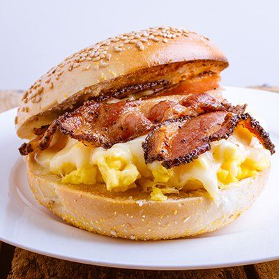 Bacon, egg, and cheese sandwich on a sesame bun on a white plate