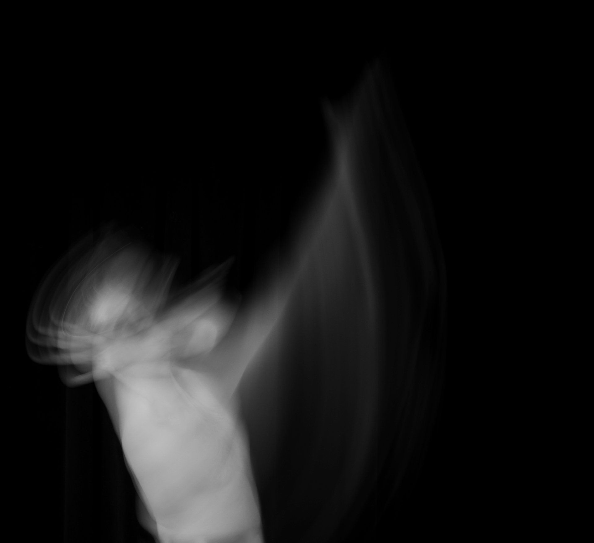 Blurred white figure raising arm against a black background.