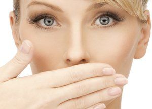 Woman with surprised expression, hand covering mouth.