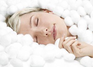 Blonde woman sleeping peacefully, surrounded by white cotton balls.