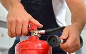 Two hands operating a fire extinguisher