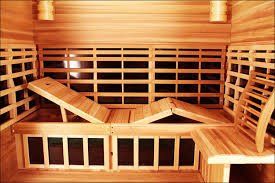 Wood-paneled sauna with wooden benches and backrests in warm lighting