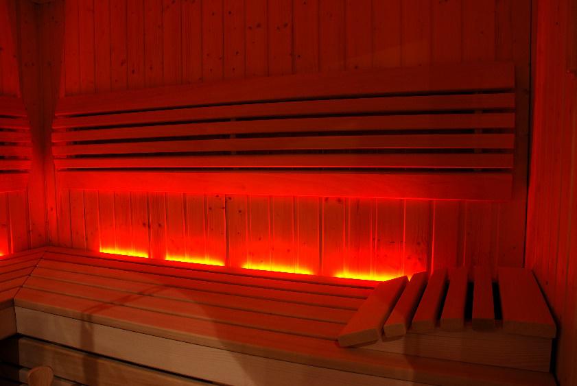 Red-lit wooden sauna benches and wall panels, glowing with heat inside an empty sauna.