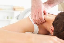 Massage therapist stretching a client’s neck and shoulder on a treatment table