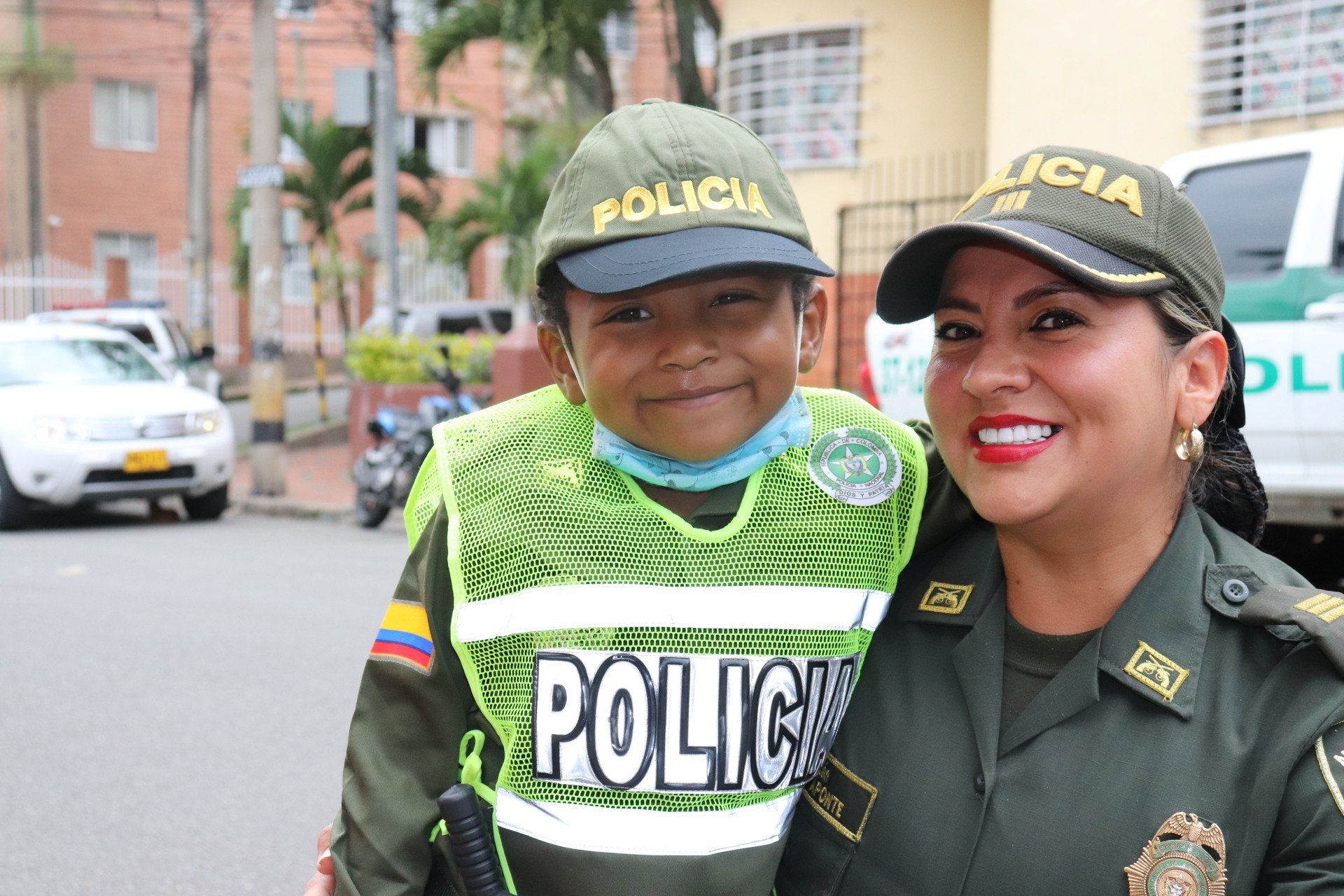 Un niño con uniforme de policía posa con un oficial de policía sonriente en una calle de la ciudad.