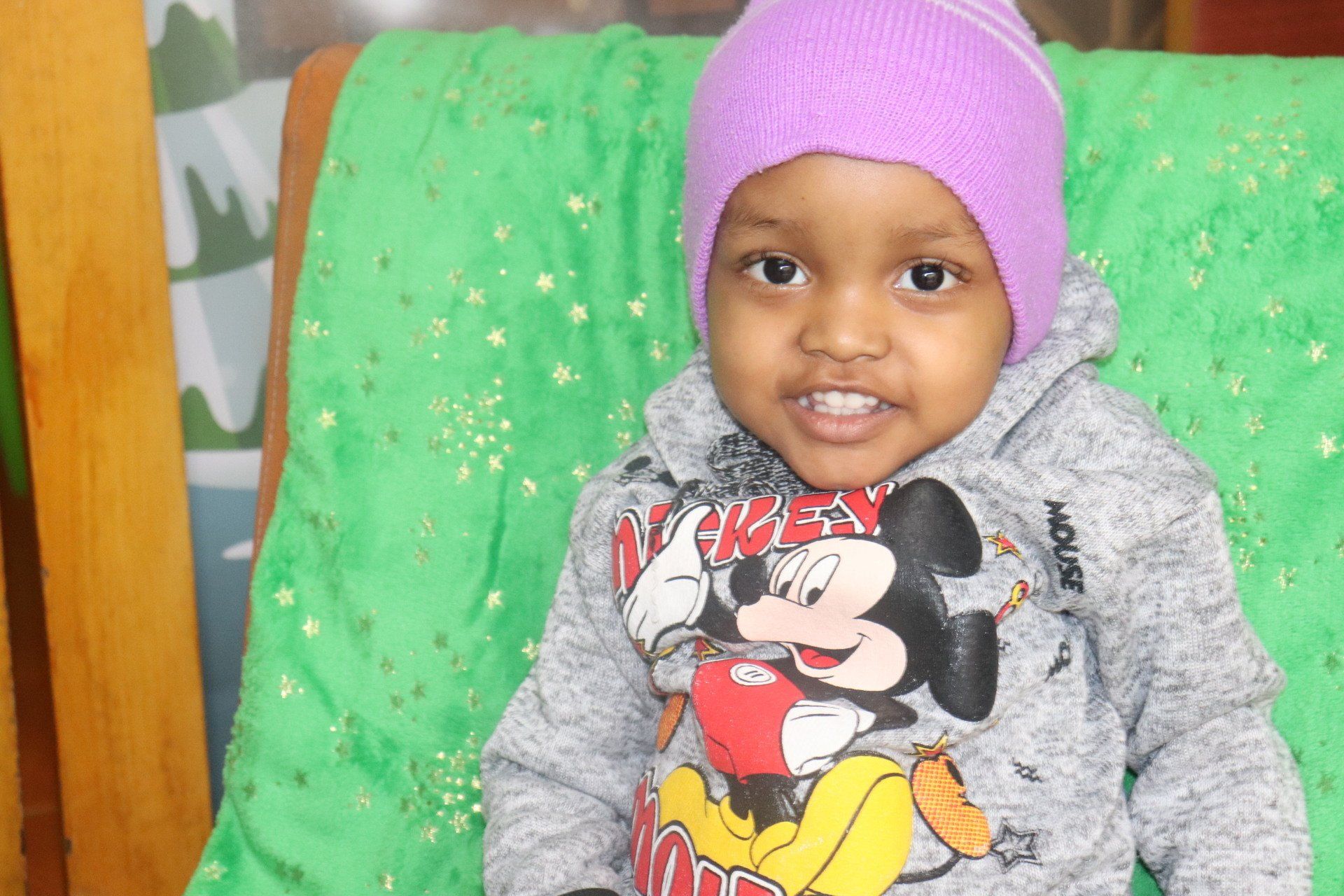 Un niño que viste un sombrero morado y una sudadera con capucha de Mickey Mouse
