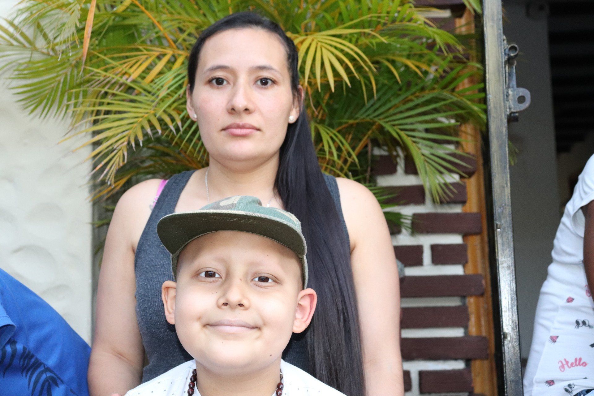 Mujer y niño, probablemente en una casa, sonriendo a la cámara. El niño lleva sombrero.