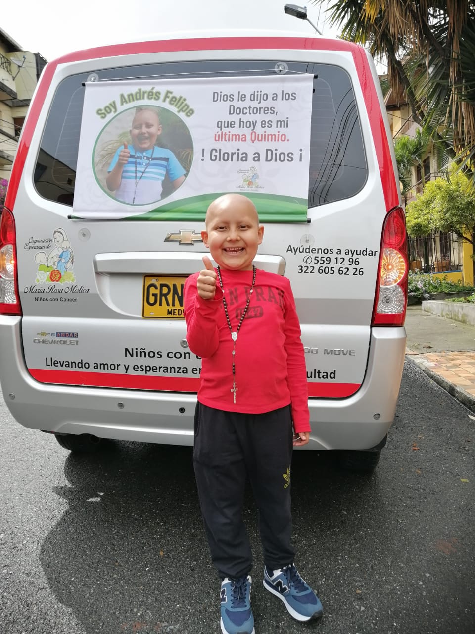 Un niño con una camisa roja sonríe y hace un gesto de aprobación con el pulgar hacia arriba