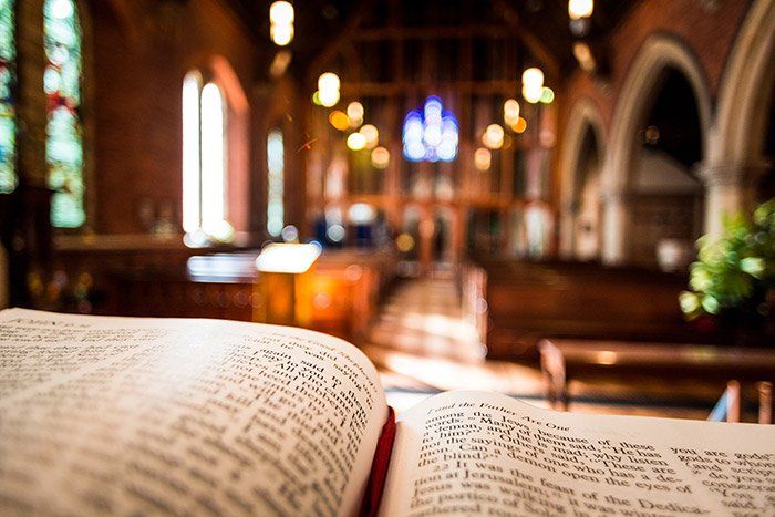 Open book in a warmly lit church with arched aisles in the background
