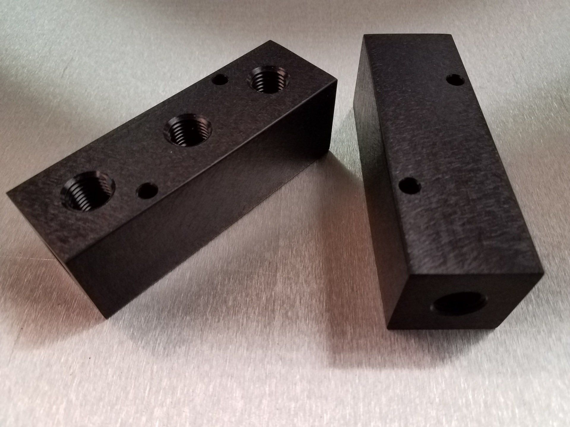 Two black blocks with holes in them are sitting on a table.