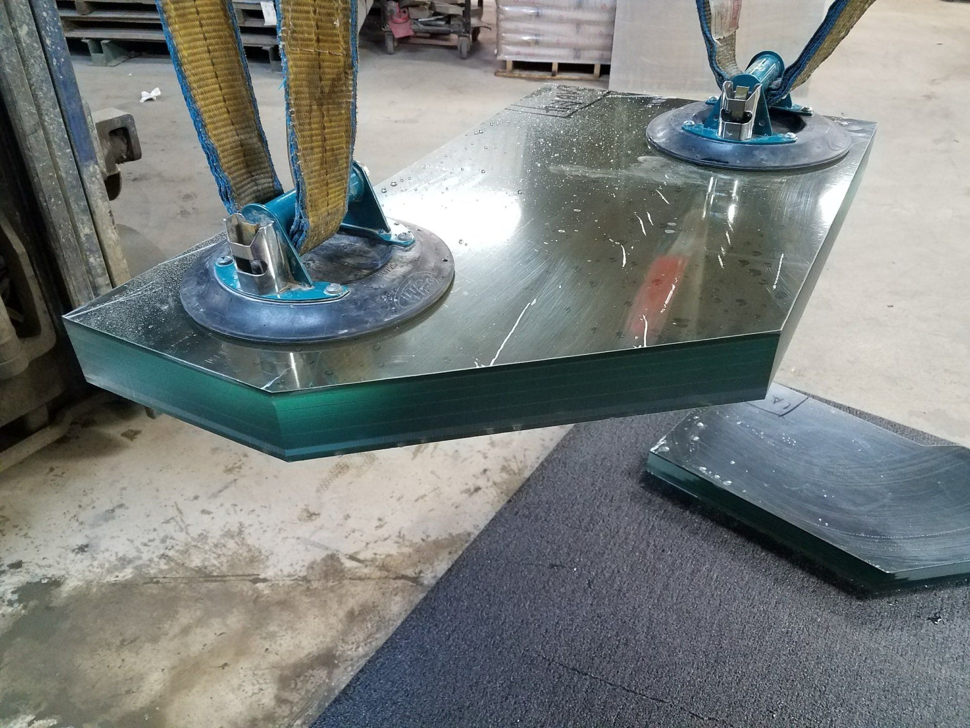 A piece of glass is being lifted by a machine.