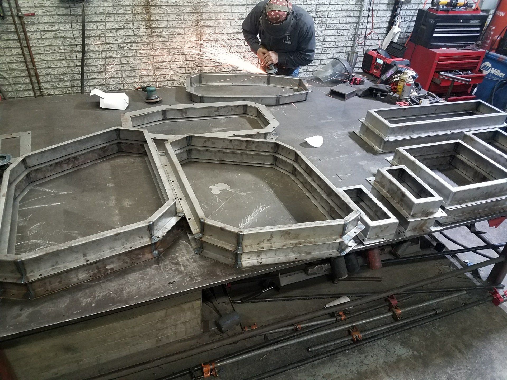 A man is welding metal pieces on a table in a factory.