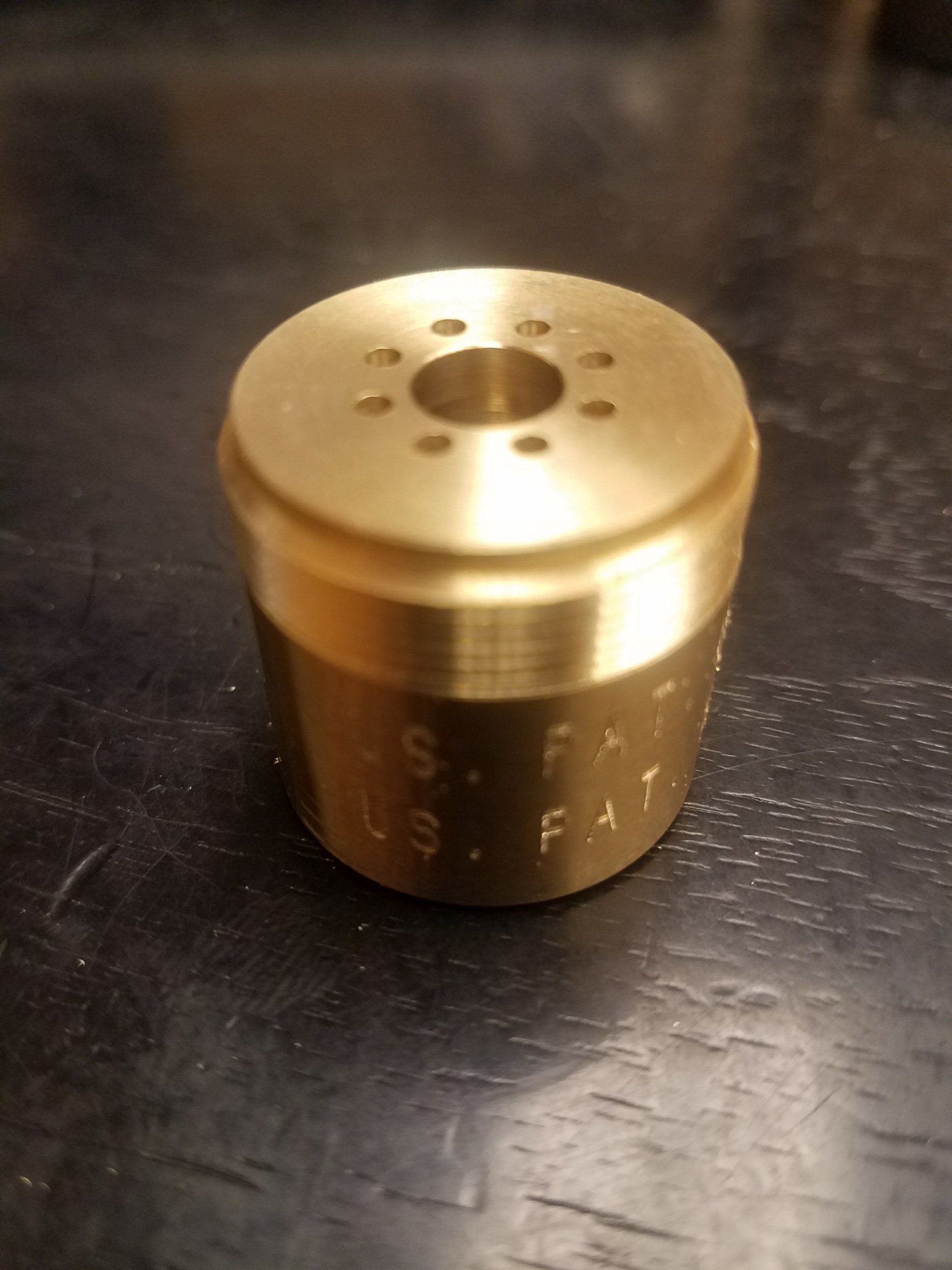 A brass cylinder with a hole in the middle is on a table