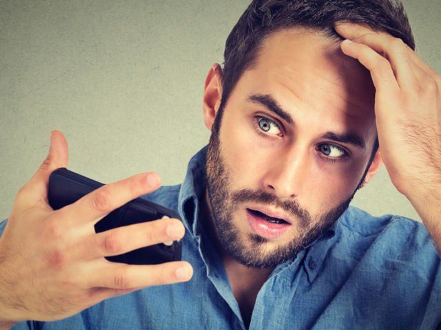 A man is combing his hair with a comb on a blue background.