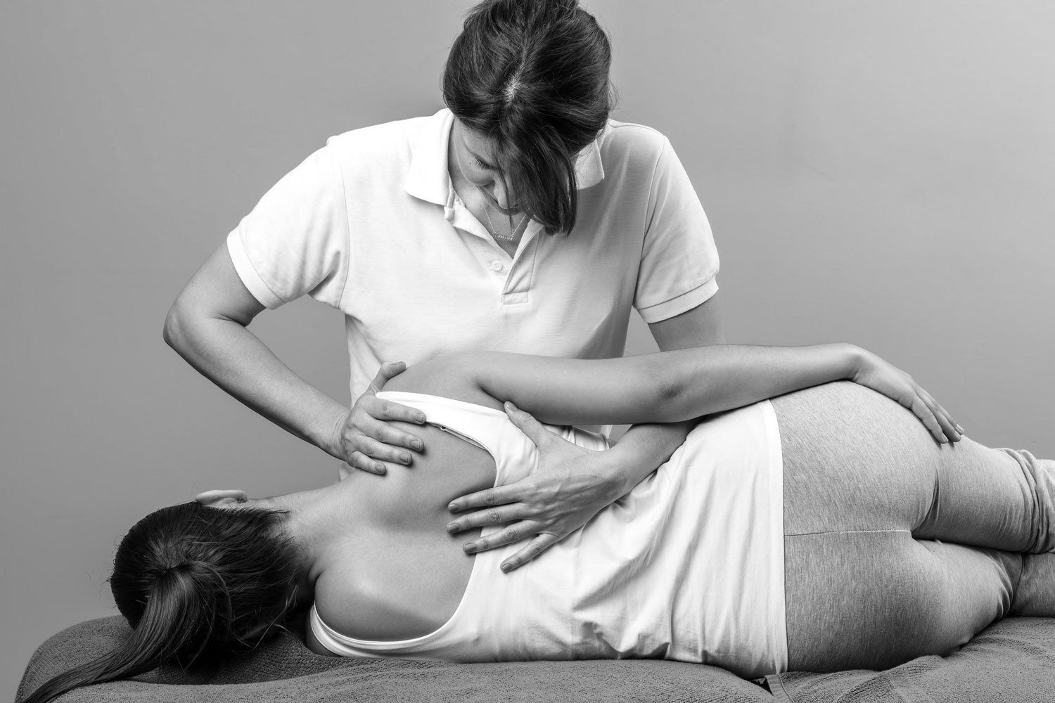 Close up of female osteopath doing shoulder blade therapy on young woman.