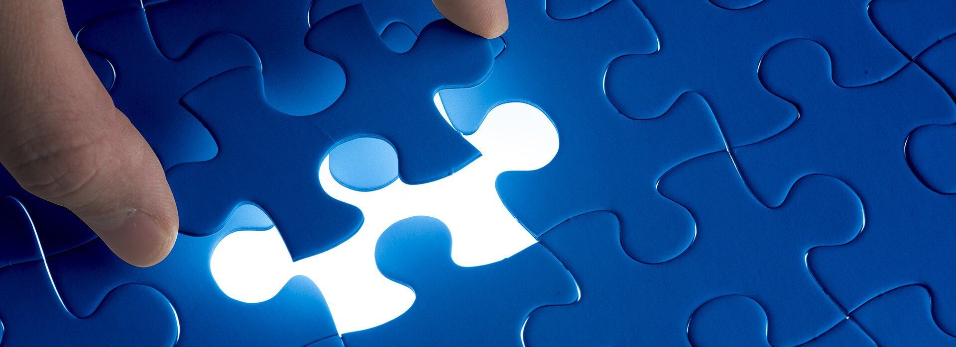 photo of jigsaw missing a piece being placed by a hand