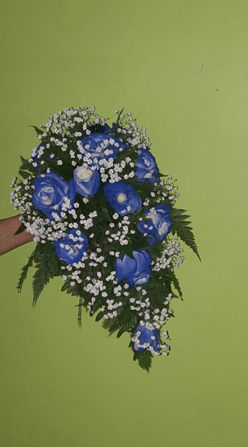 Una persona sostiene un ramo de rosas azules y flores de bebé.
