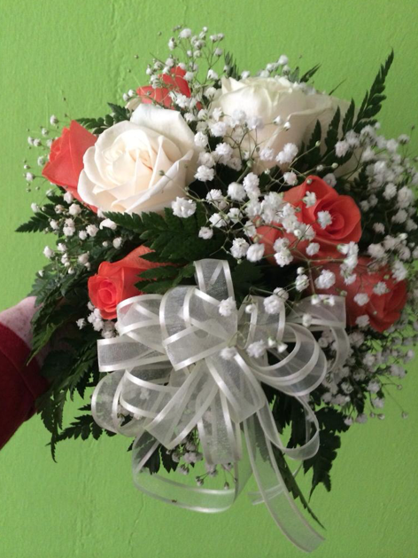 Una persona sostiene un ramo de rosas y flores de aliento del bebé.