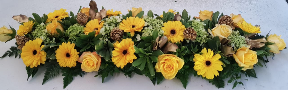 Un ramo de flores amarillas con hojas verdes sobre una mesa.