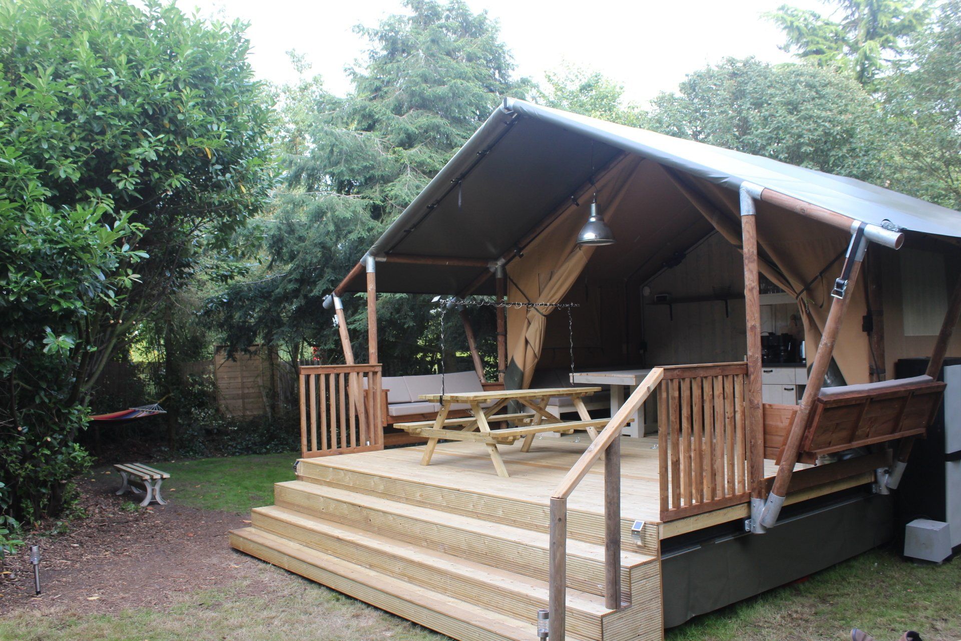 Een tent met een houten terras en een picknicktafel erop.