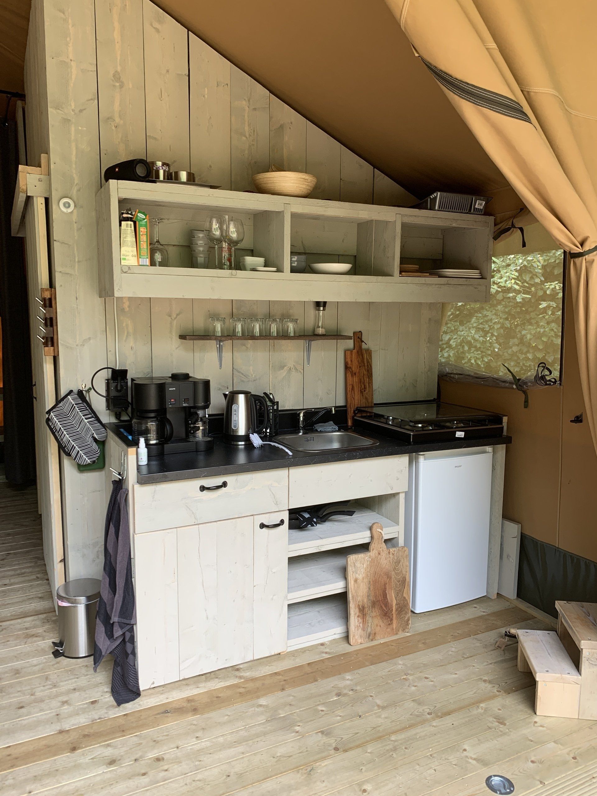 Een keuken in een tent met een gootsteen, fornuis en koelkast.