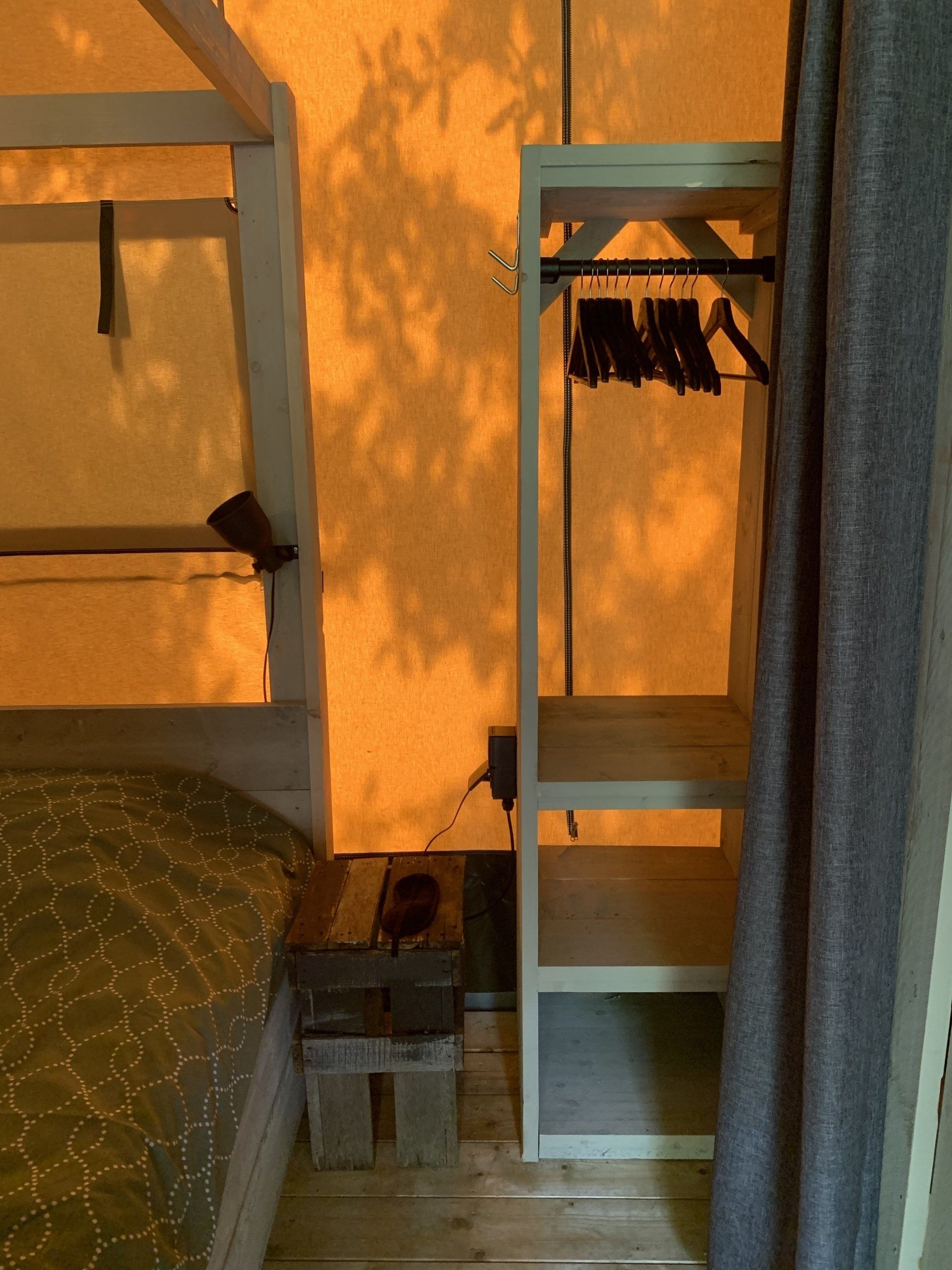 Een slaapkamer met een bed en een plank met kleren erop
