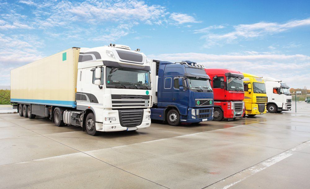 A row of semi trucks are parked in a parking lot.