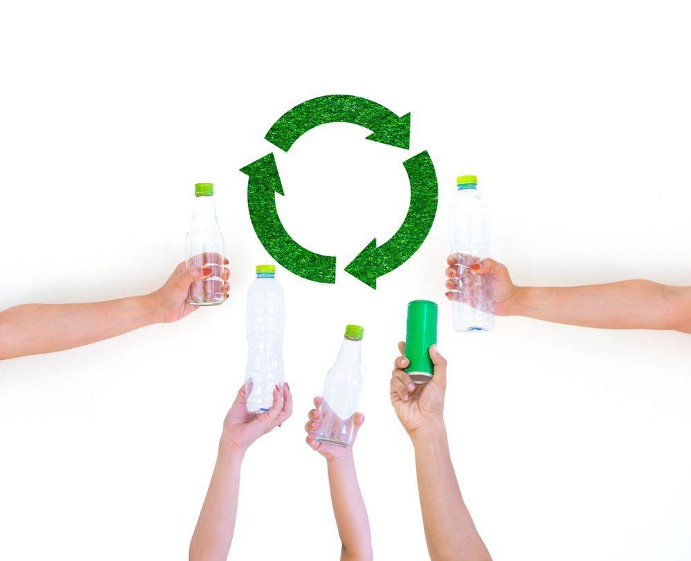 A group of people are holding plastic bottles and cans in their hands.