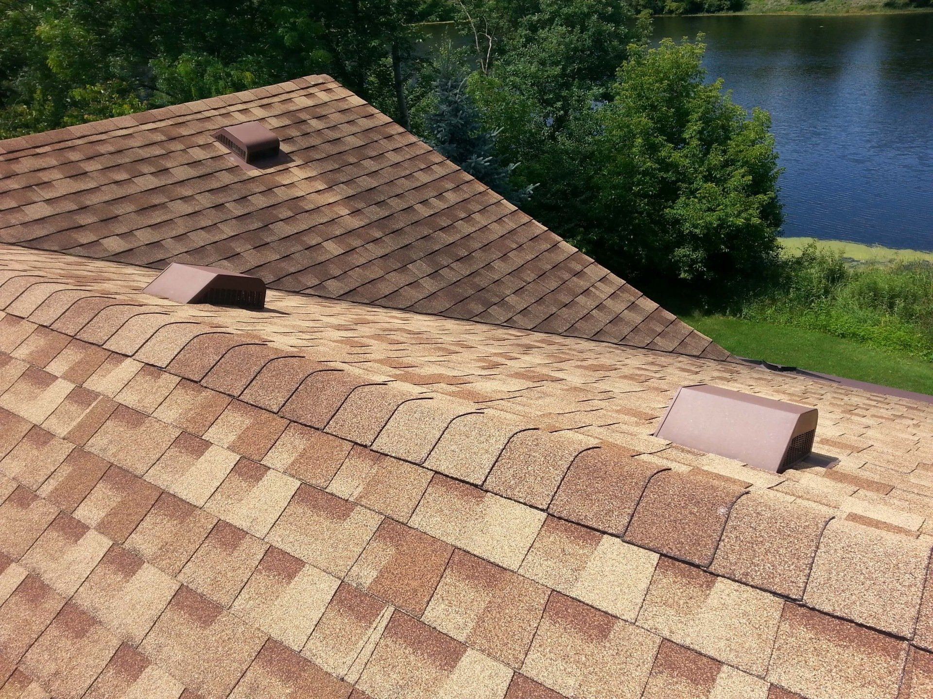 A close up of a roof with a lake in the background.