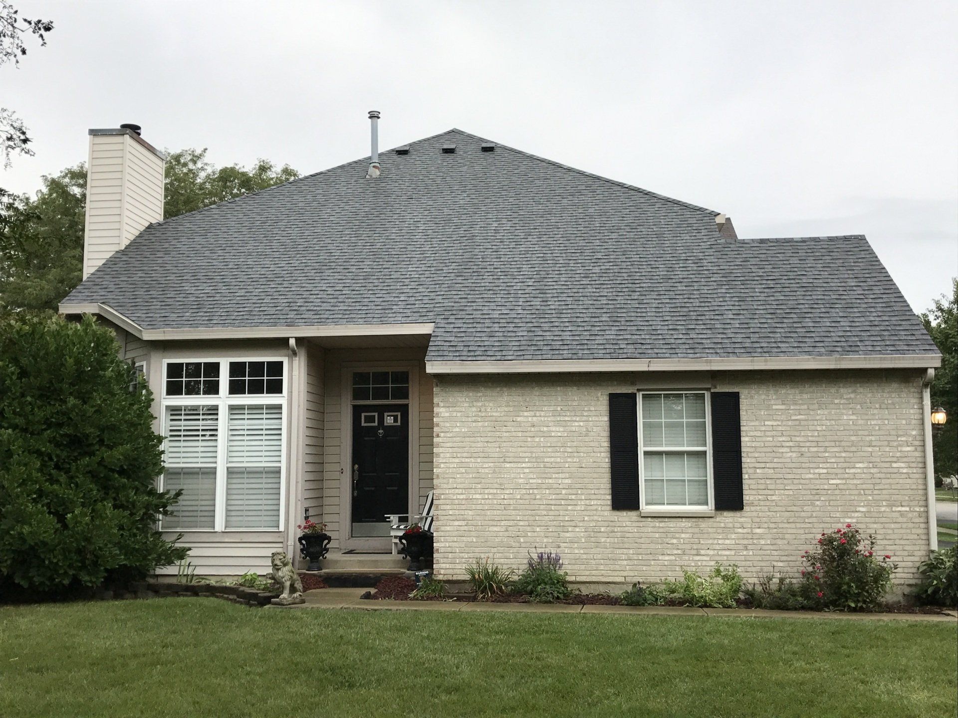 A brick house with a gray roof and black shutters