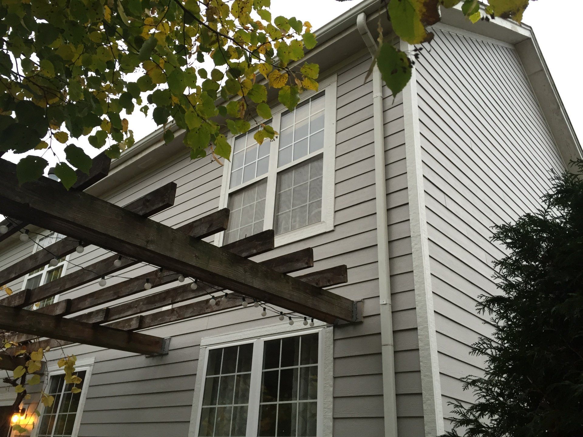 A white house with a pergola on the side of it