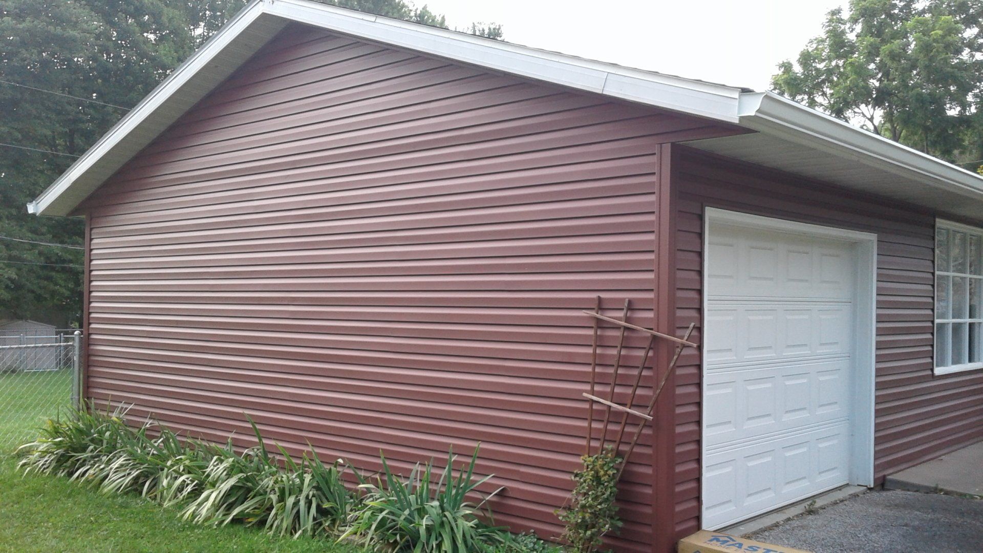 A garage with a red siding and a white garage door.