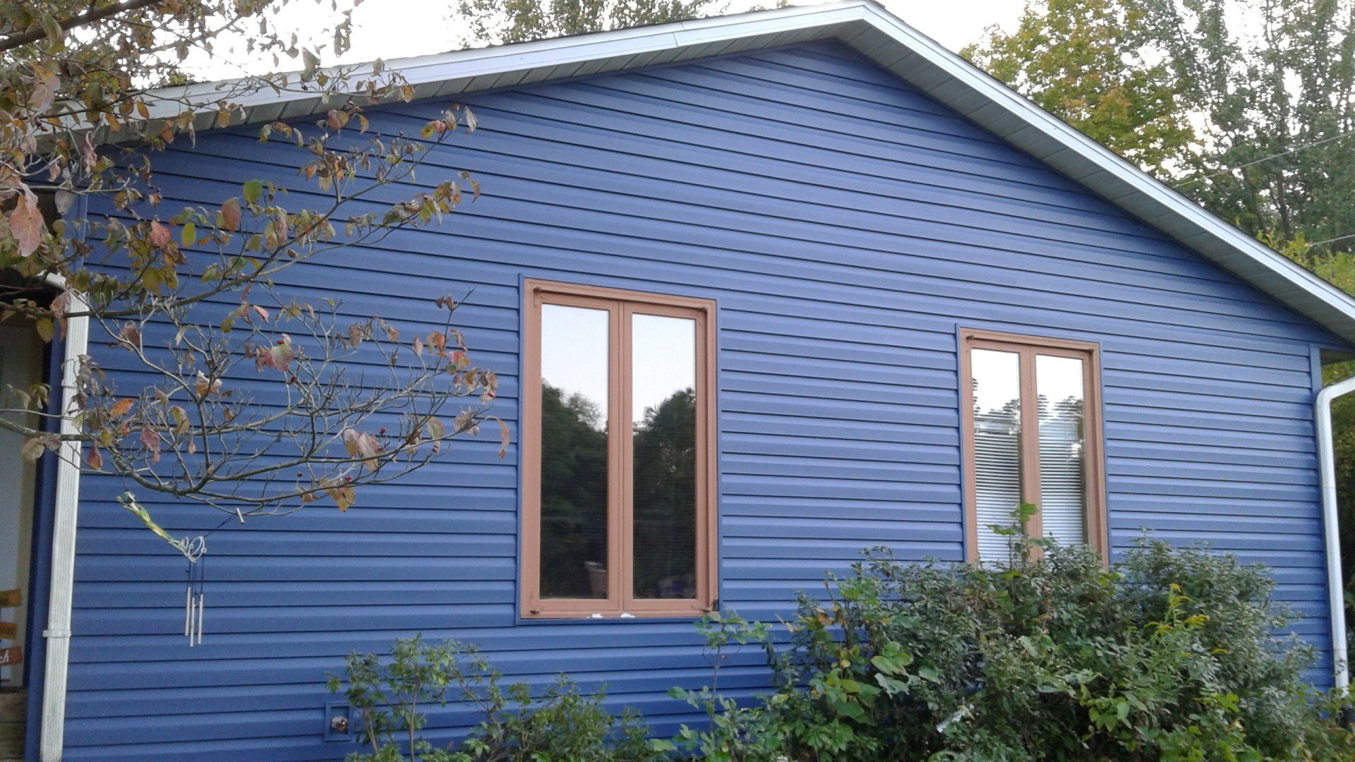 A blue house with two windows and a roof