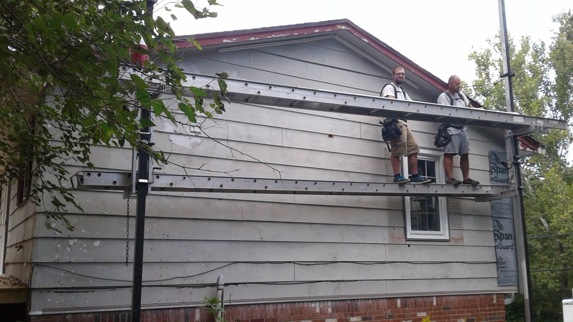 A man is standing on a scaffolding on the side of a house