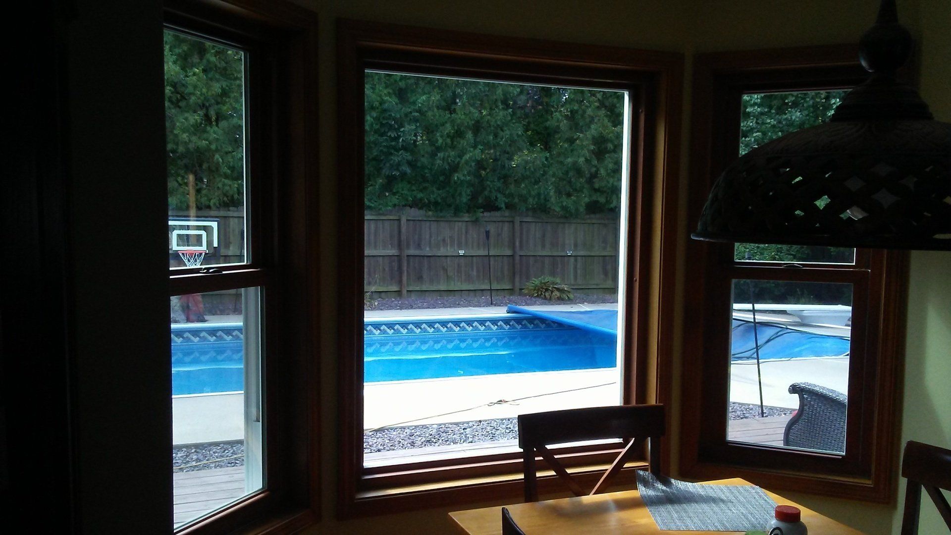 A dining room with a table and chairs and a view of a pool.