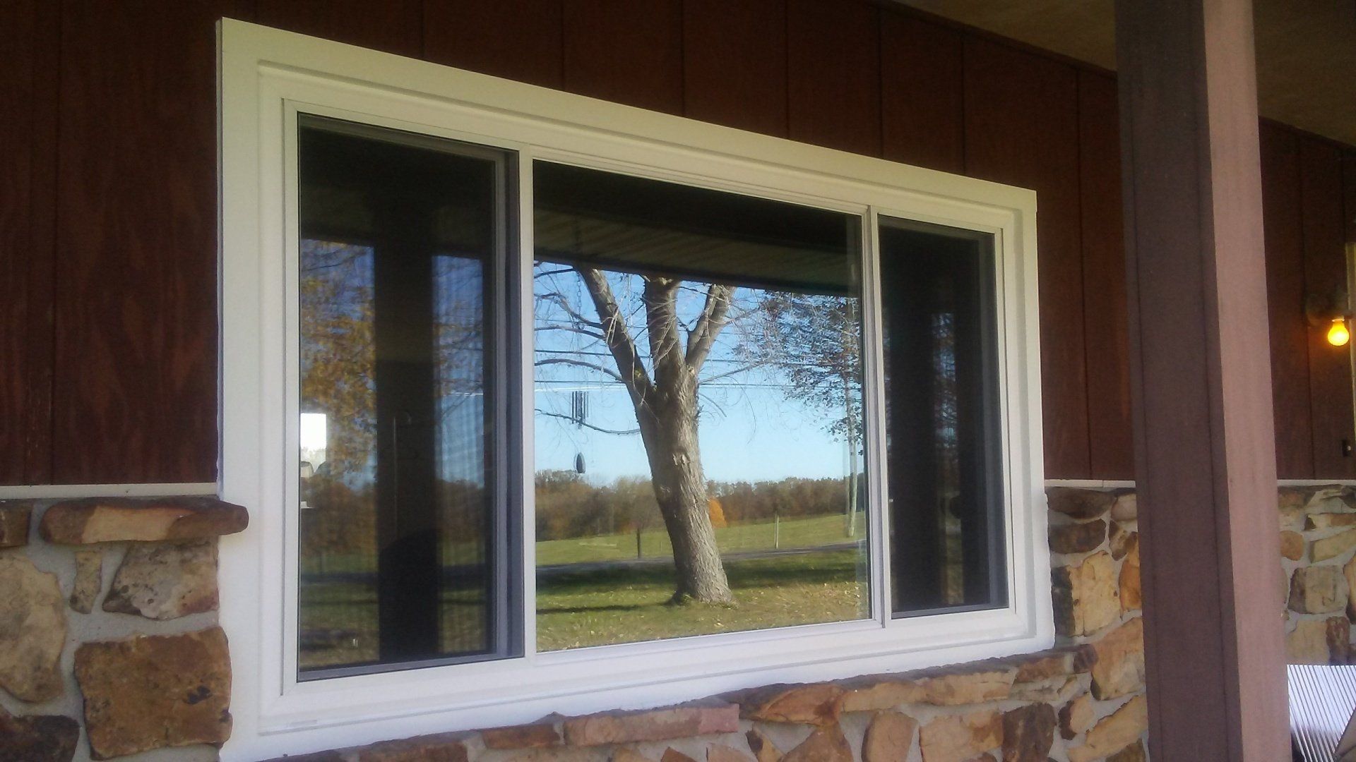 A large window on the side of a house with a view of a tree.
