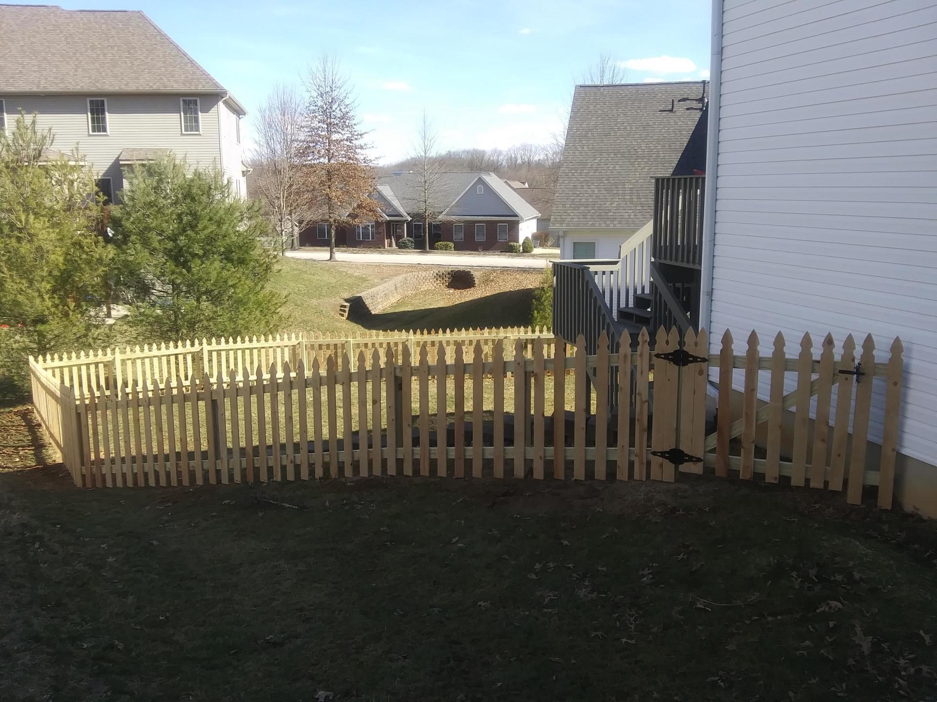 A wooden picket fence is in the backyard of a house
