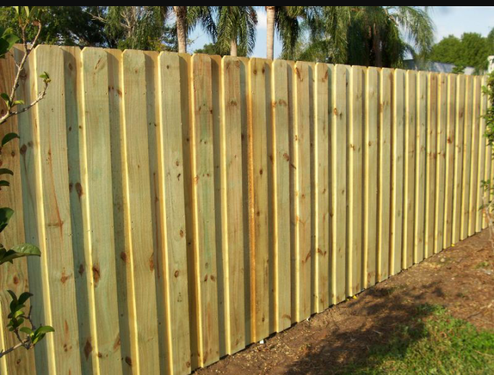 A wooden fence is surrounded by grass and trees