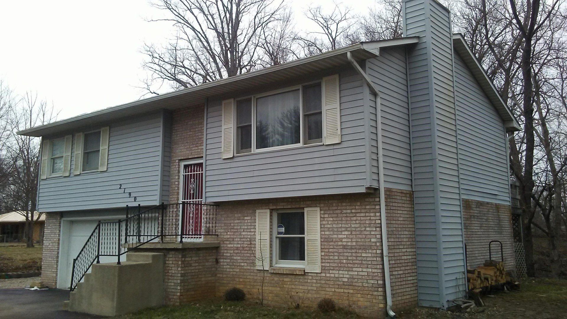 A brick house with a blue siding and white shutters