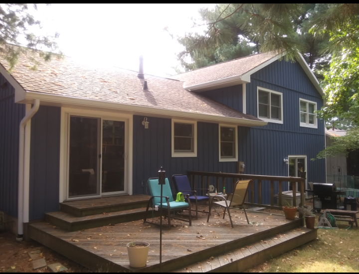 A blue house with a deck in front of it