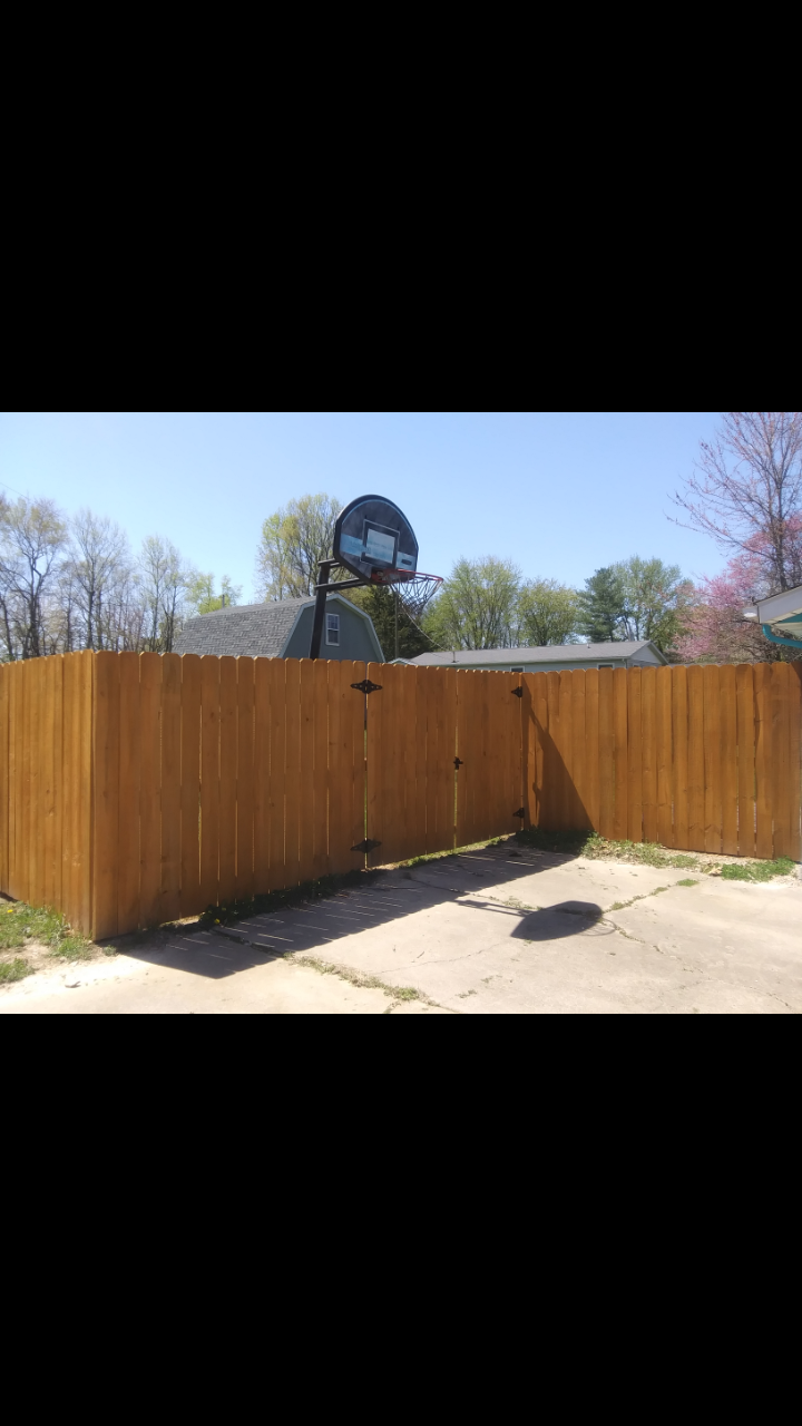 A wooden fence with a basketball hoop on top of it.