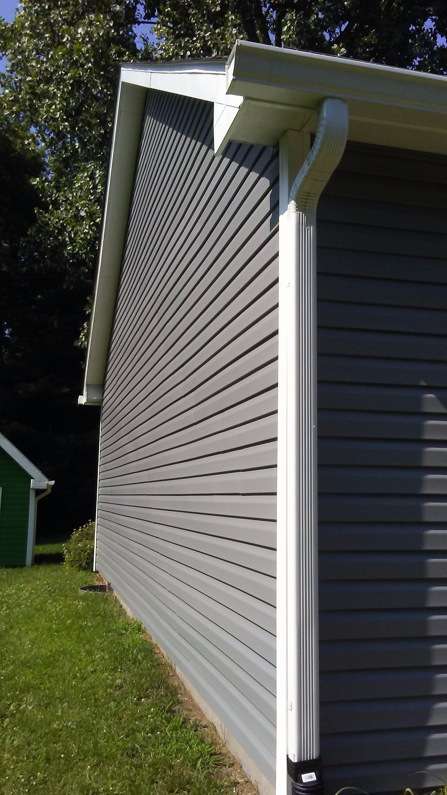 A black cat is standing on the side of a house.