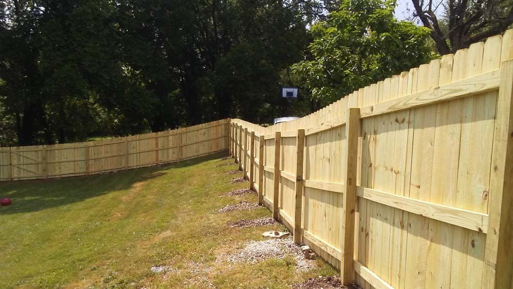 A wooden fence is sitting on top of a lush green field.