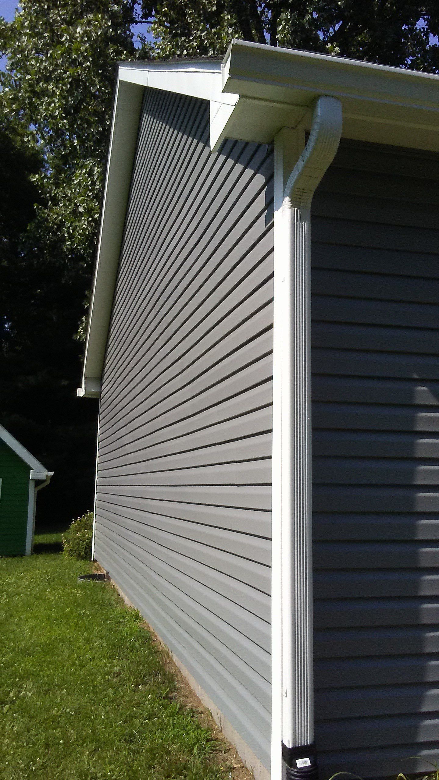 A gray house with a white gutter on the side of it.