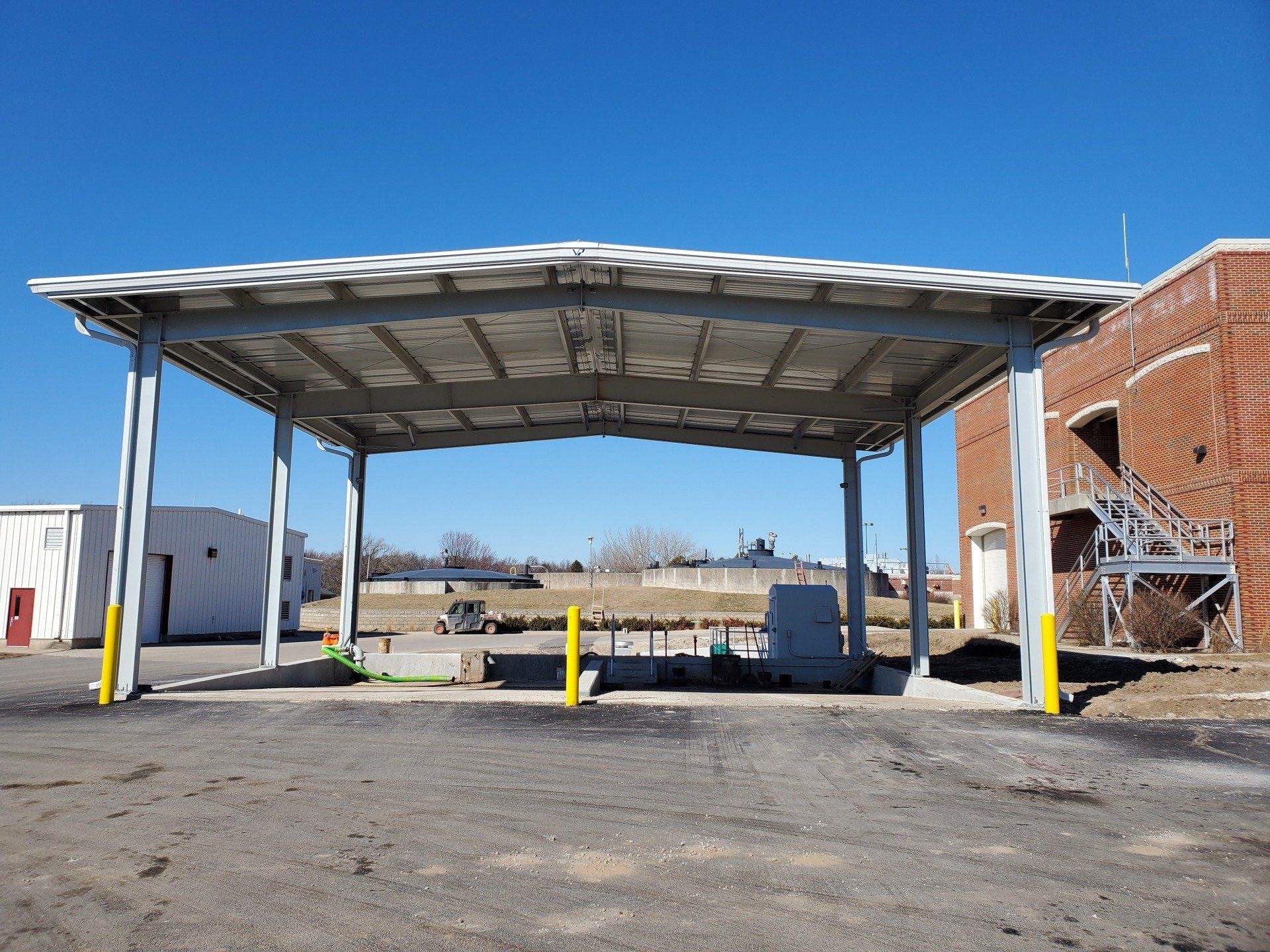 A parking lot with a canopy over it and a brick building in the background