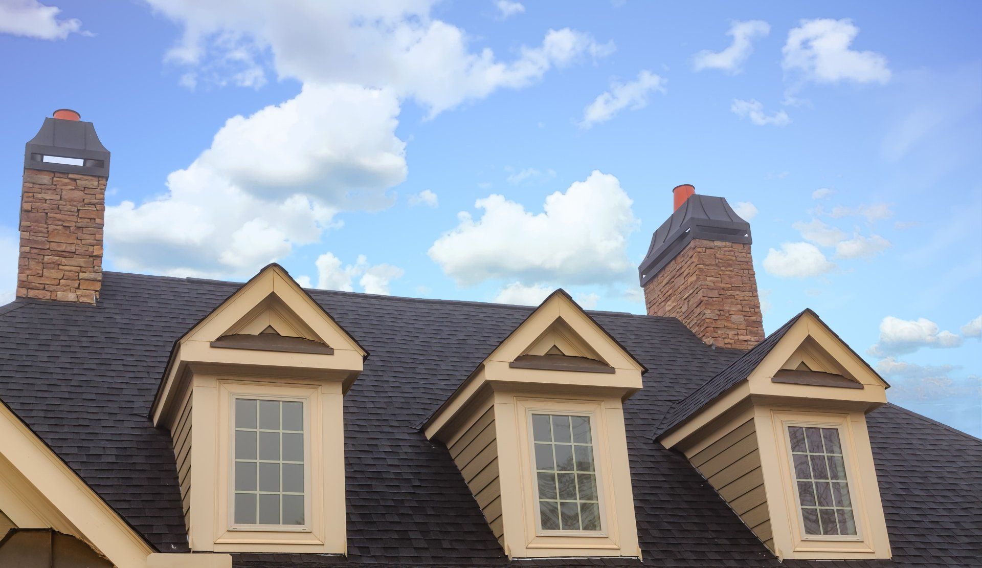The roof of a house with a lot of windows and chimneys