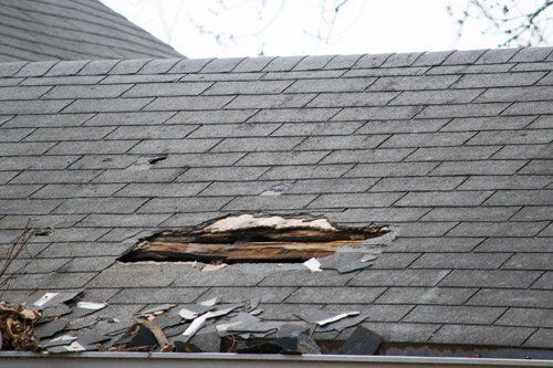 A roof with a hole in it and shingles missing.