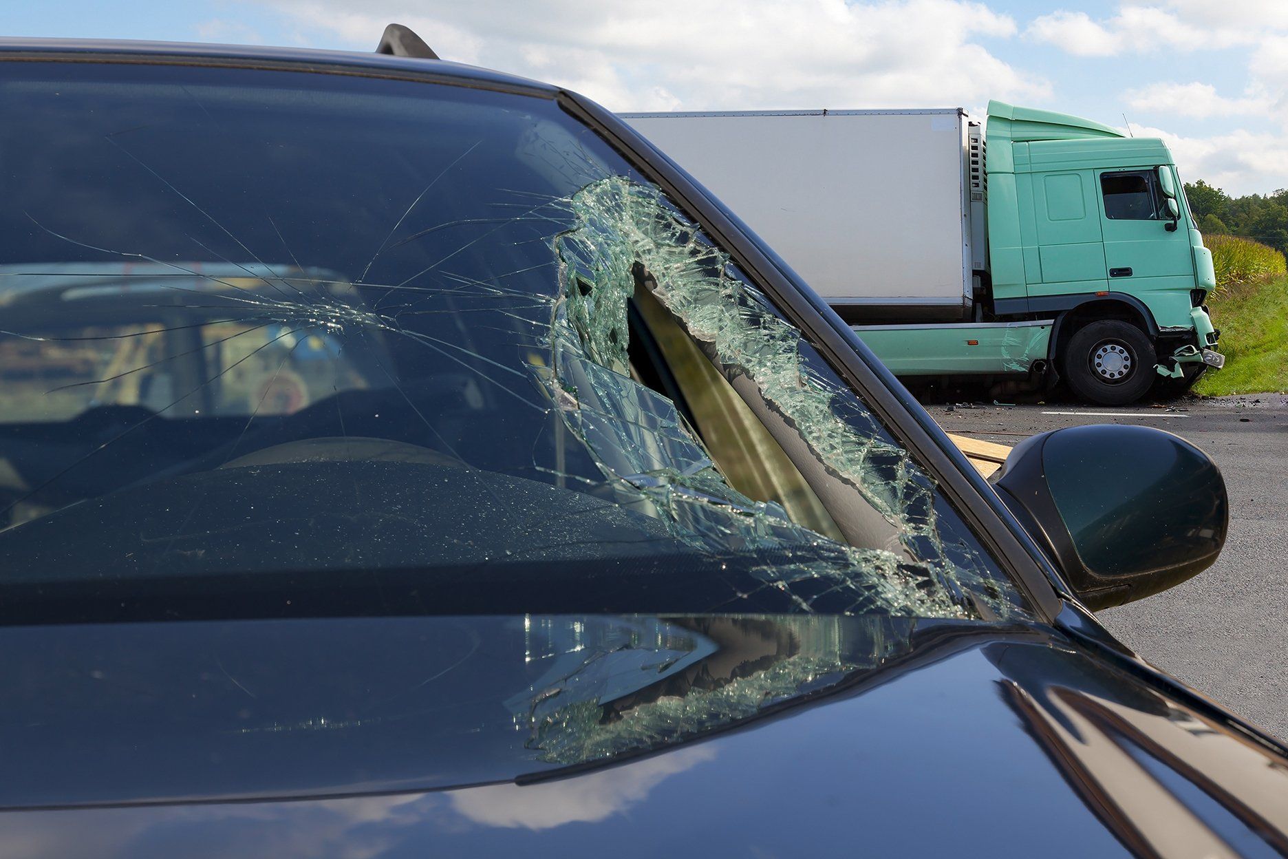 Broken car windshield; a green semi-truck in background.